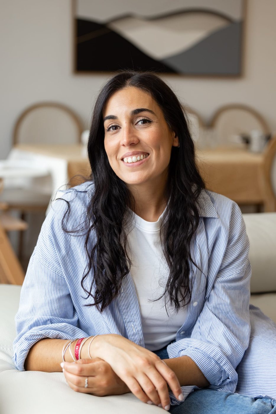 Ana Puente sentada en un sofá, sonriendo